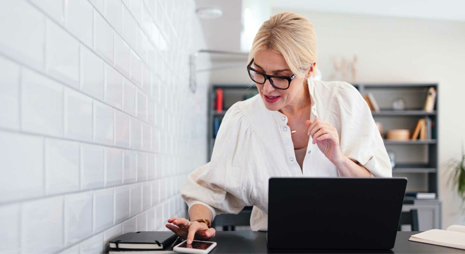 Businesswoman working at desk with a laptop and phone